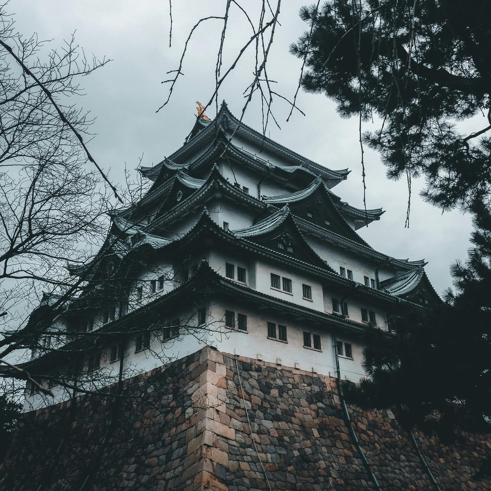 Majestic castle with traditional Japanese architecture set against a cloudy sky.