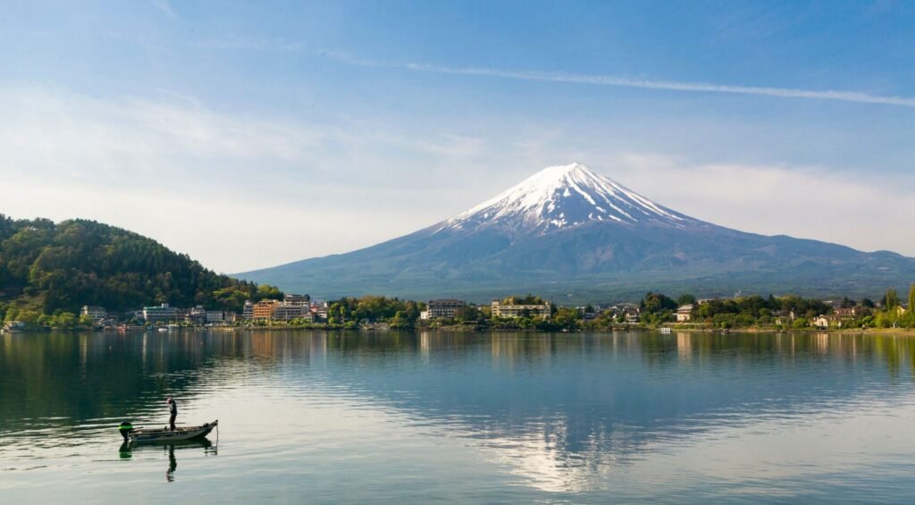 A serene view of Mount Fuji with a fishing boat on Lake Kawaguchi, Japan.