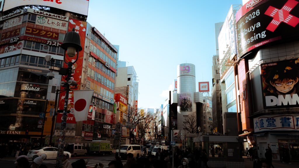 Vibrant daytime scene at Shibuya Crossing, Tokyo, with colorful advertisements and crowds.