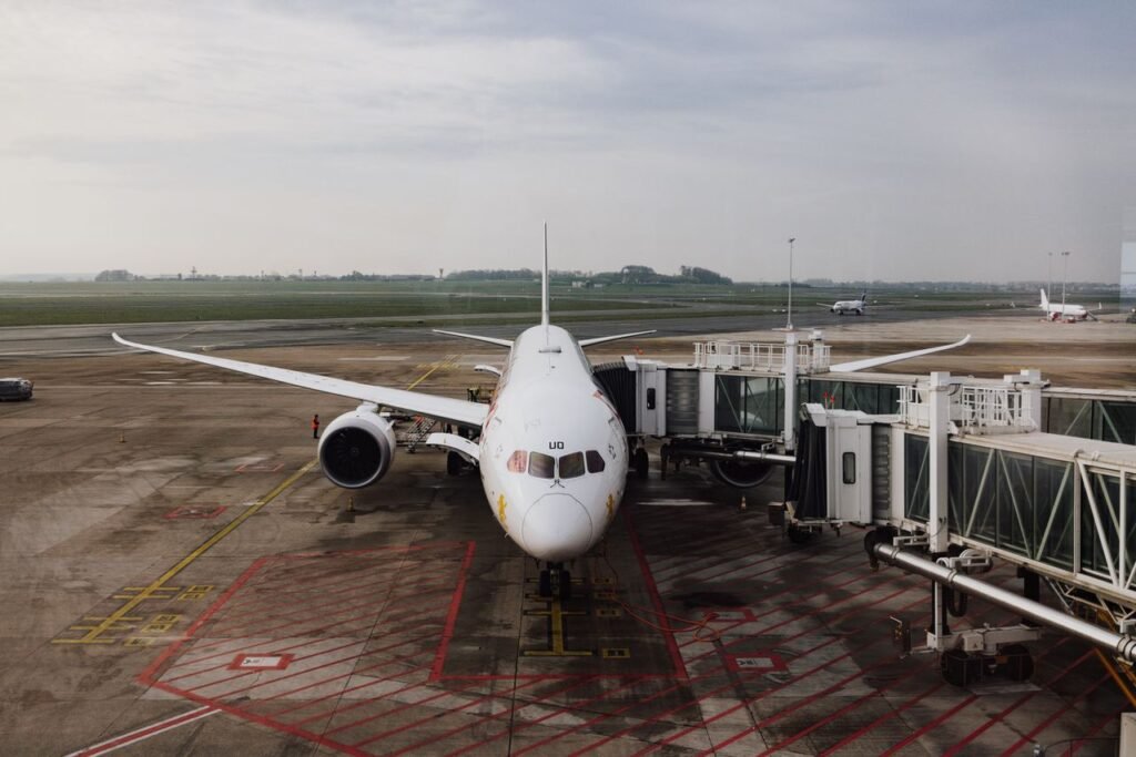 Tokyo Airport Transfer Guide: Narita, Haneda, Trains & Private Transfers A modern jet airplane docked at an airport terminal gate, ready for boarding on a cloudy day.