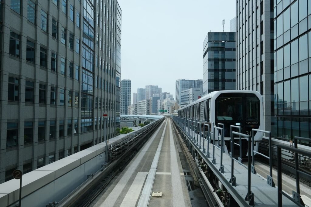 Monorail train moving through Tokyo's urban skyline with towering buildings.