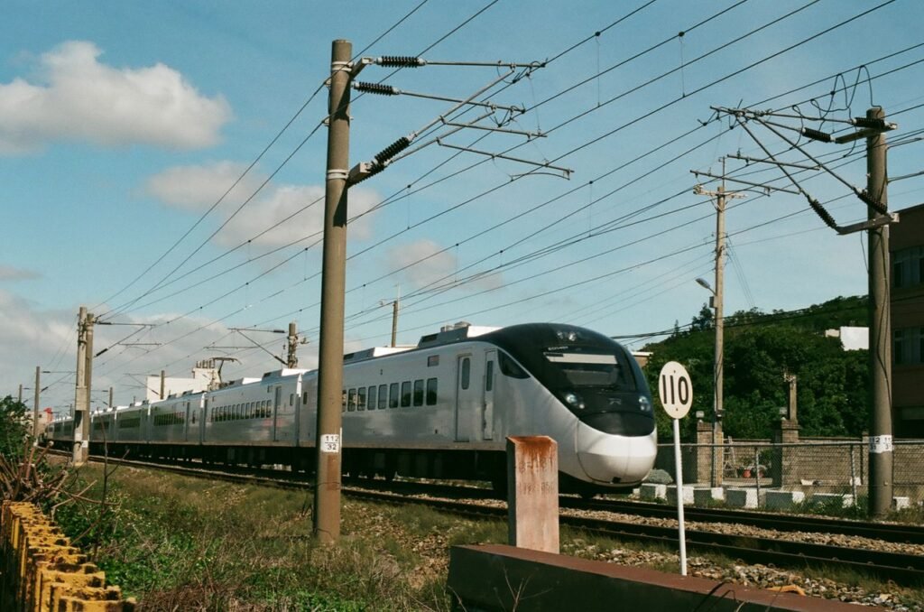 High-speed train moving through Taiwan's scenic countryside on a sunny day.