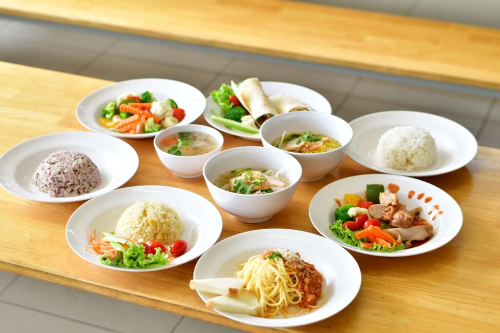 A variety of Asian and Italian dishes presented beautifully on a wooden table, showcasing diverse flavors.