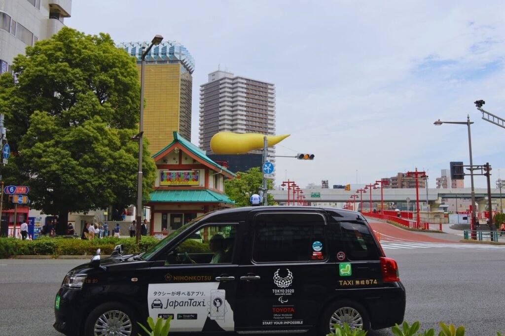 Black Japan Taxi in Tokyo with Asahi Beer Hall and cityscape in the background.