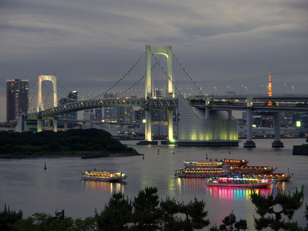 Stunning view of Tokyo's Rainbow Bridge illuminated at night with colorful boats on the bay.