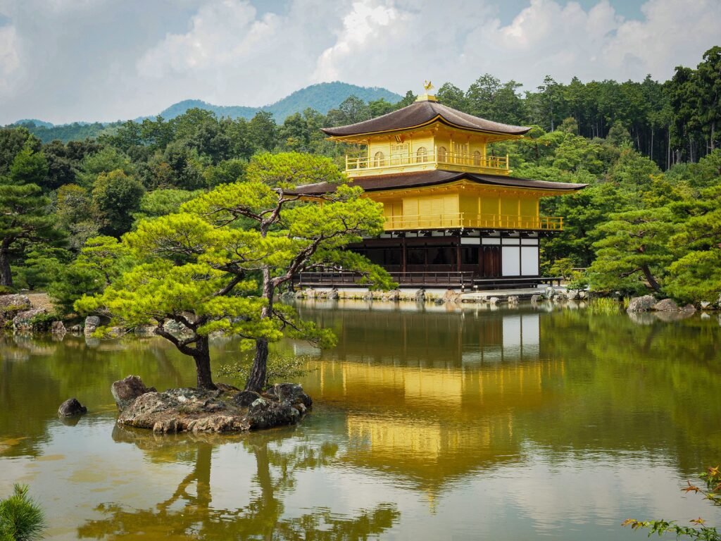 Scenic view of the Golden Pavilion at Kinkaku-ji with lush greenery and reflection in the pond.