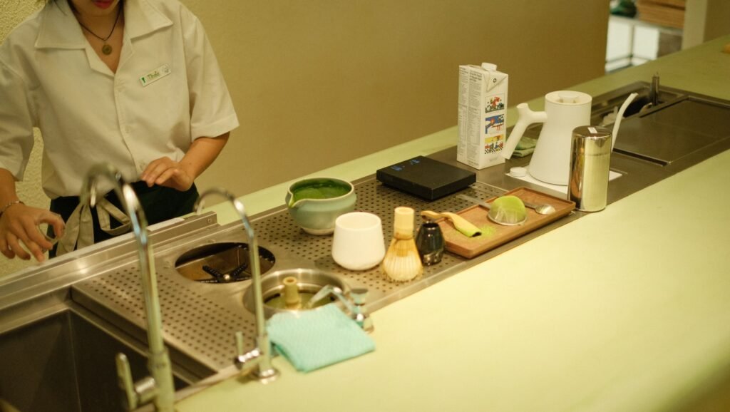 A person prepares matcha tea in a modern kitchen setup.