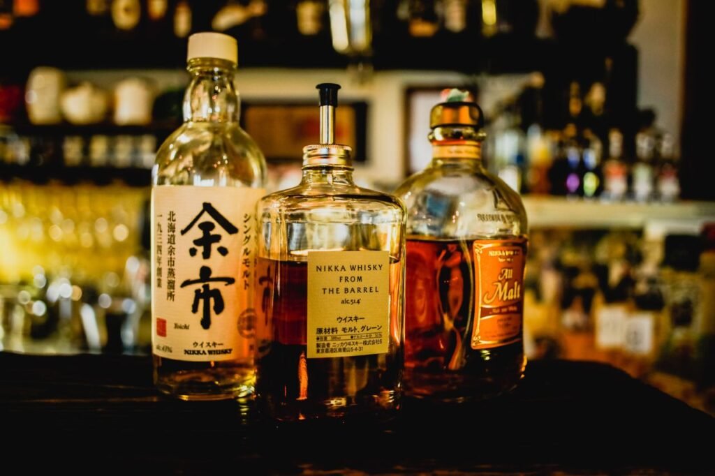 Japanese Whiskey Day Trip: Best Distillery Tours from Tokyo, Osaka & Kyoto Selection of Japanese whisky bottles displayed in a dimly lit bar setting.