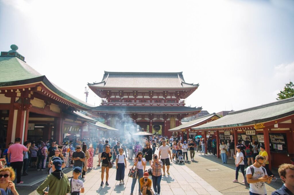 Crowd of travelers strolling on pavement near aged Asian church under shiny sky in Japan