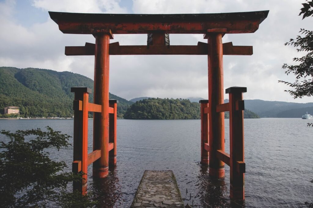 Scenic view of the iconic Torii gate at Lake Ashi in Hakone, Japan, surrounded by lush mountains.